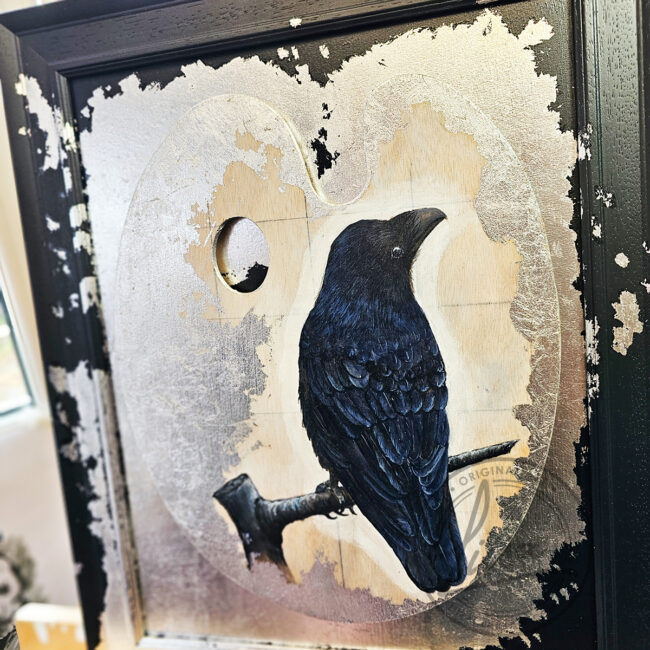 Close up of Original Painting of a Crow on an Artist palette set with Silver Leaf in a Black Frame by Liisa Clark