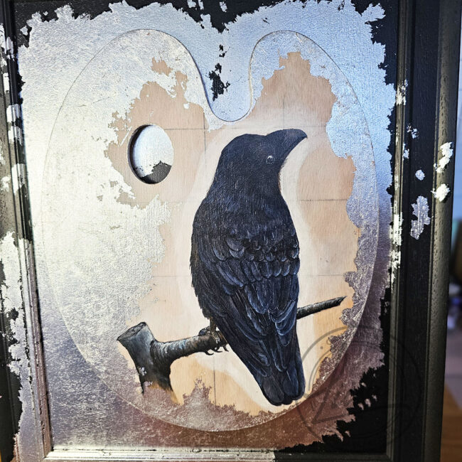Close up of Original Painting of a Crow on an Artist palette set with Silver Leaf in a Black Frame by Liisa Clark