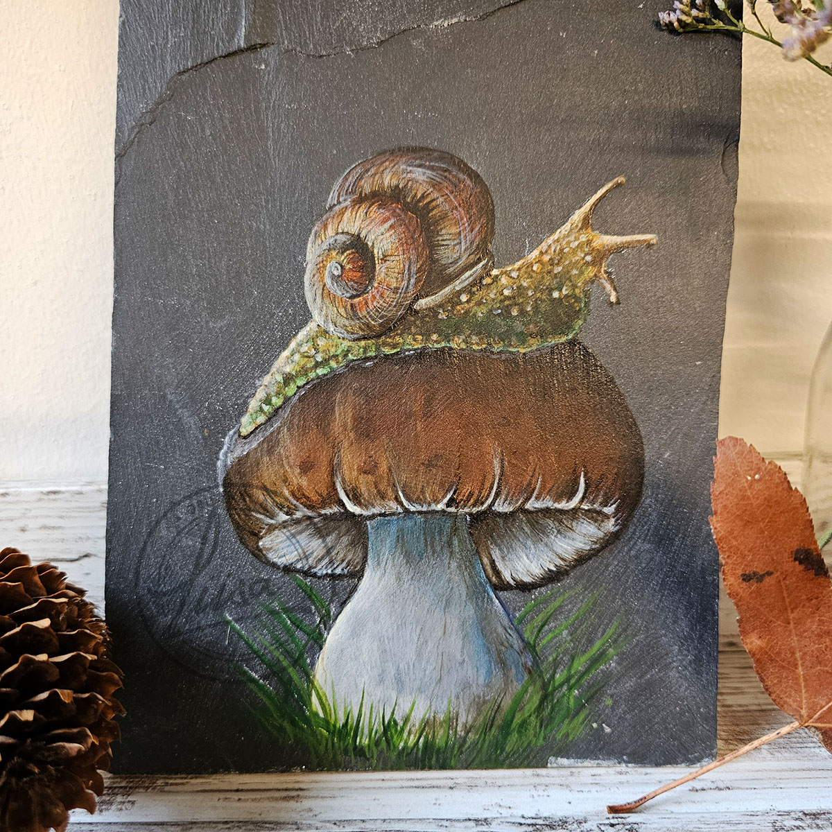 Close-up detail of the snail and toadstool acrylic painting on Welsh slate, showing brushwork and texture on the stone surface