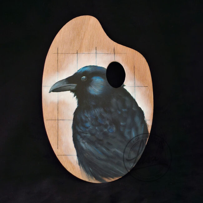 Original oil painting of a raven on a birch wood artist palette by Liisa Clark Art, featuring deep black and blue iridescent feathers.