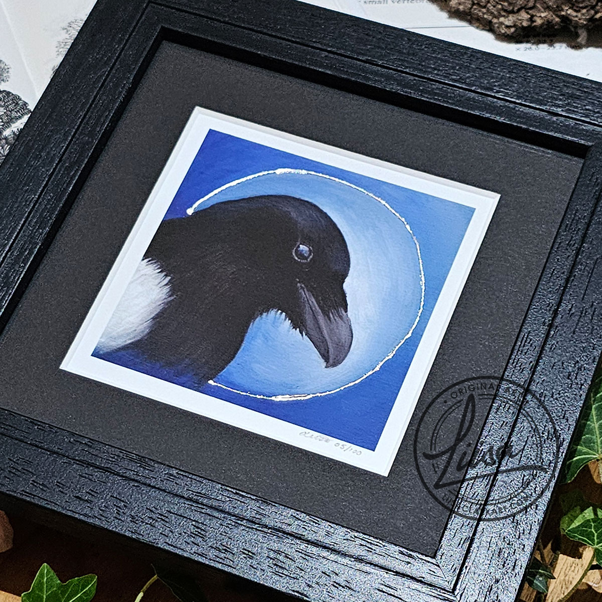 Close-up of hand embellished Silver leaf detailing on a framed magpie giclée print from the Blue Corvid Series by Liisa Clark Art.