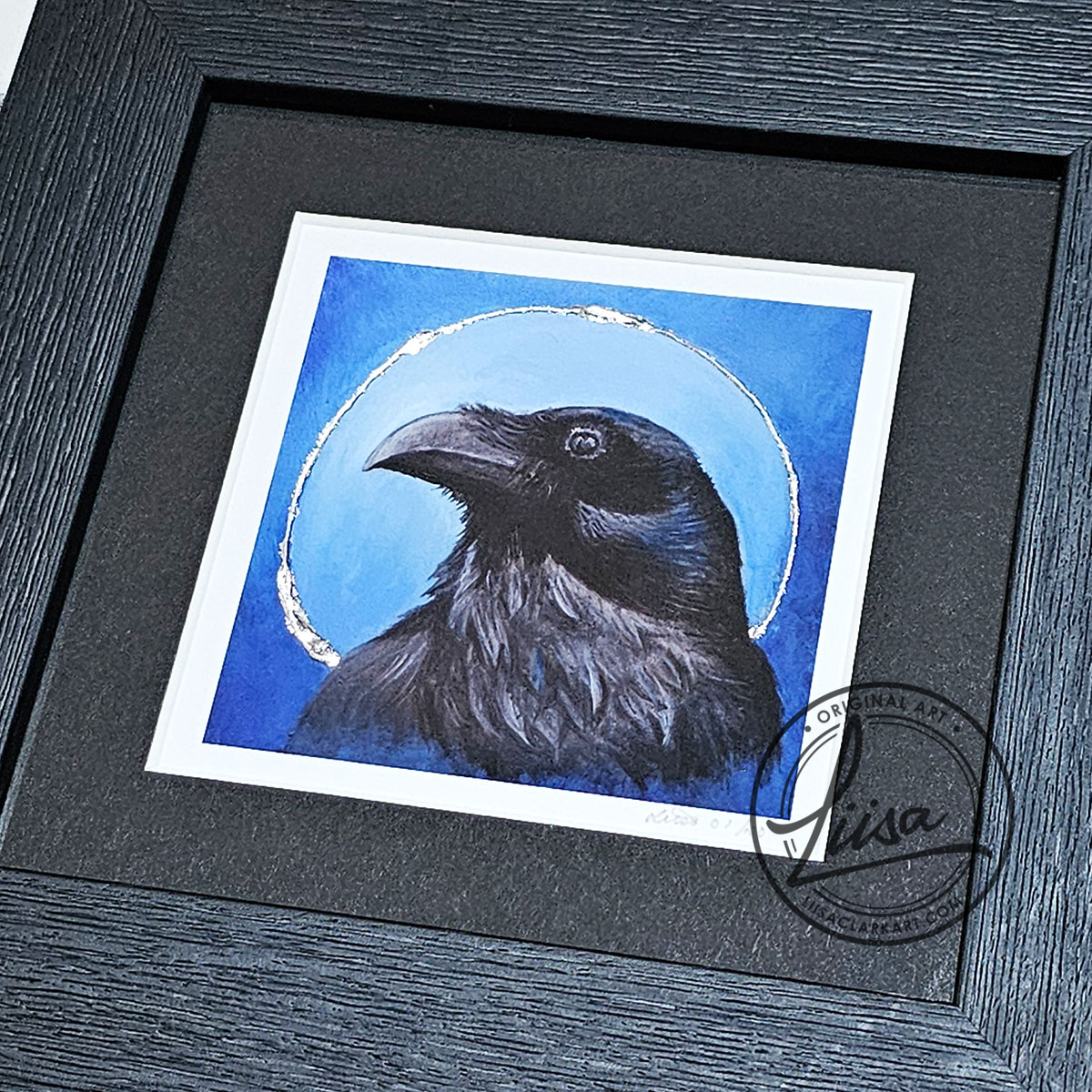 Close-up of a raven portrait print with silver leaf halo detailing from the Blue Corvid Series by Liisa Clark Art